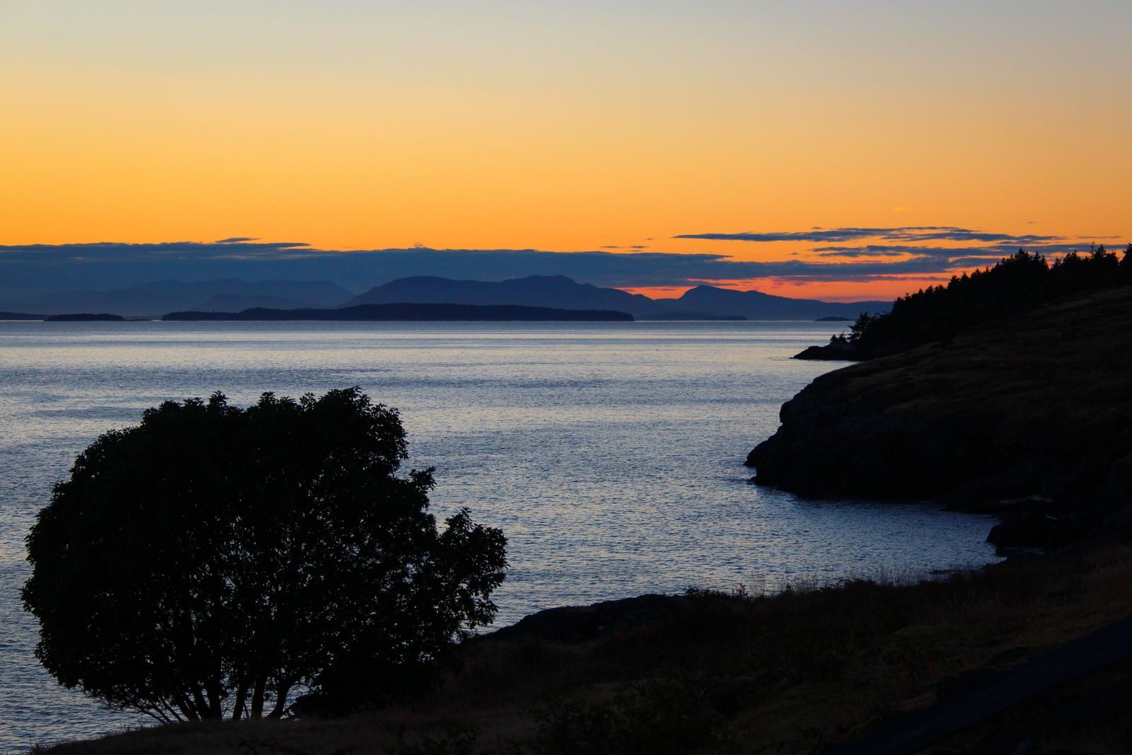 Sunset over calm water and island silhouettes in the Pacific Northwest