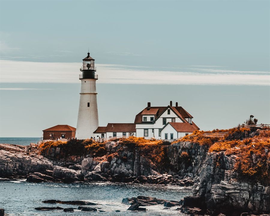 Portland Head Light and keeper’s house above autumn grasses on the rocky Maine shore