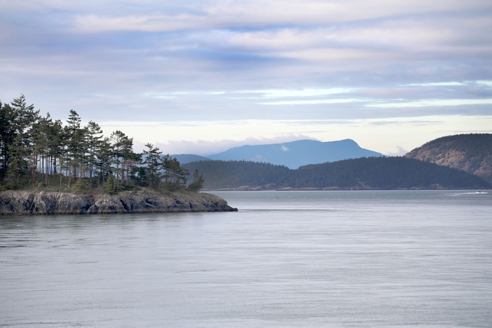 Evergreen islands and mountains along the water, typical scenery on Pacific Northwest cruises